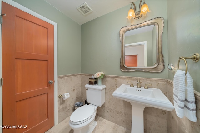 bathroom featuring tile walls and toilet