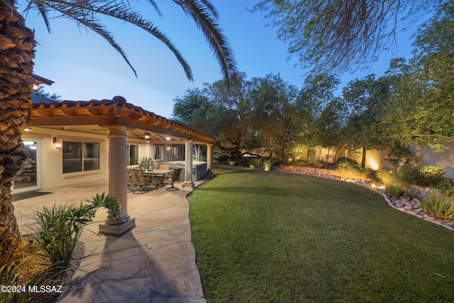 yard at dusk featuring a patio