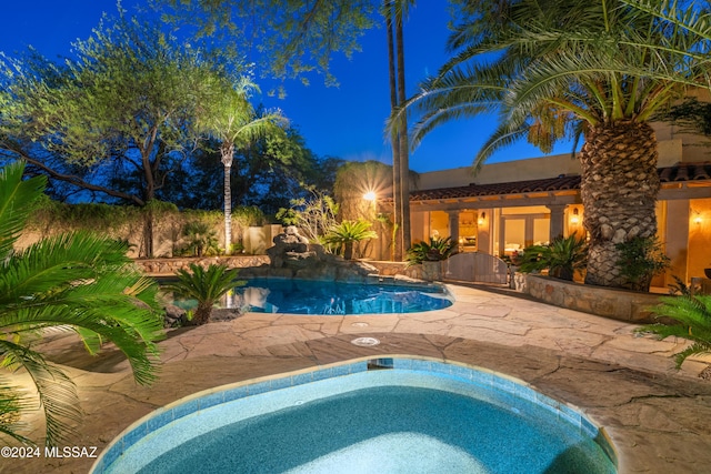 pool at twilight featuring a jacuzzi