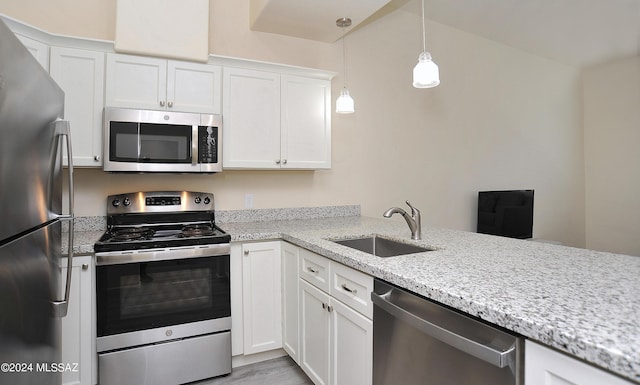 kitchen featuring sink, white cabinetry, stainless steel appliances, and hanging light fixtures