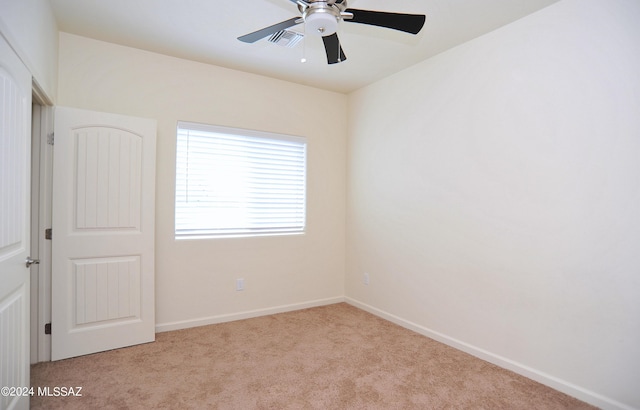 unfurnished room with light colored carpet and ceiling fan