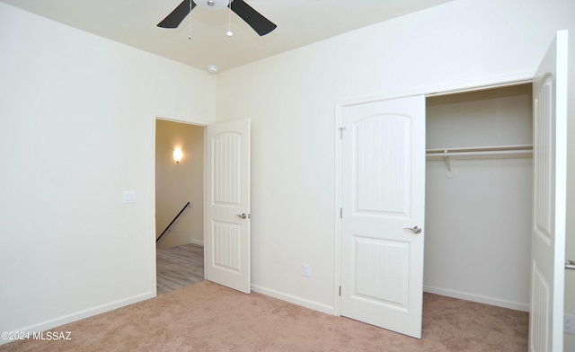 unfurnished bedroom featuring ceiling fan, a closet, and light carpet