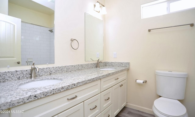 bathroom with vanity, toilet, and a tile shower