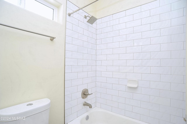 bathroom featuring tiled shower / bath combo and toilet