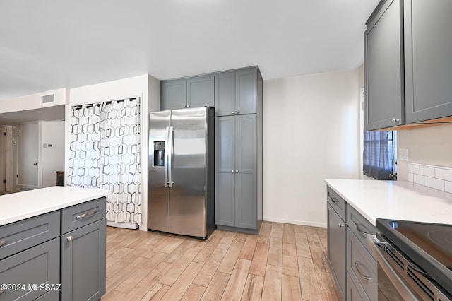 kitchen with stainless steel refrigerator with ice dispenser, gray cabinets, and light hardwood / wood-style flooring