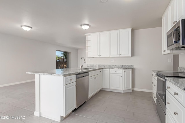 kitchen featuring sink, light stone counters, kitchen peninsula, white cabinets, and appliances with stainless steel finishes