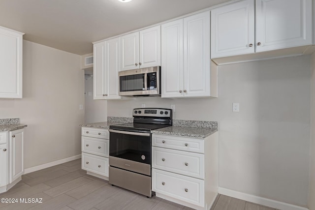 kitchen featuring light stone counters, white cabinetry, and stainless steel appliances