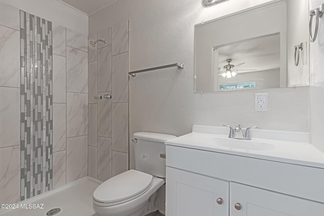 bathroom featuring toilet, ceiling fan, a tile shower, and vanity