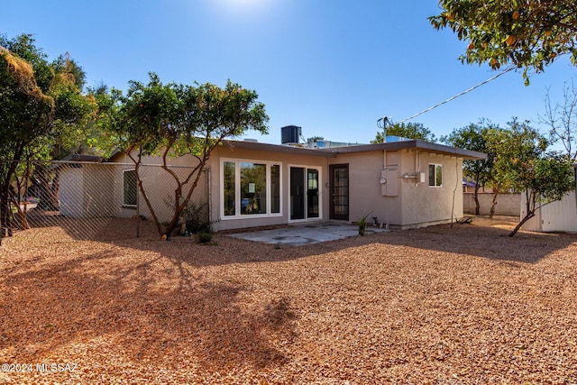 rear view of property with cooling unit and a patio