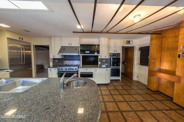 kitchen with sink, backsplash, white cabinets, and high end appliances