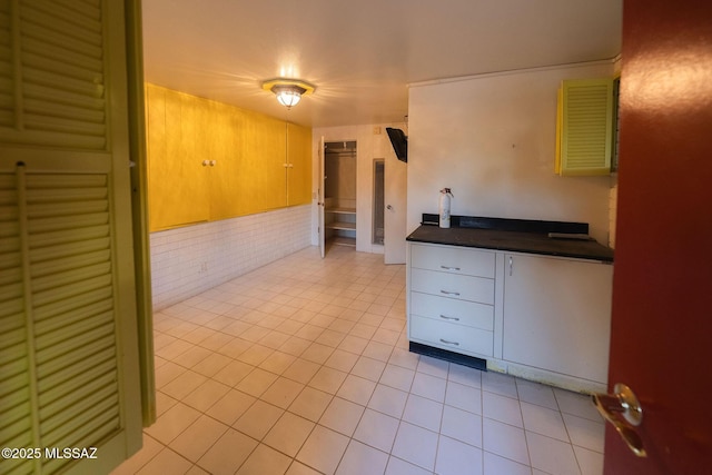 unfurnished room featuring light tile patterned flooring and brick wall