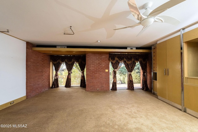 carpeted spare room with ceiling fan, brick wall, and a healthy amount of sunlight