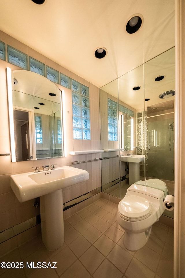 bathroom featuring toilet, a healthy amount of sunlight, tile patterned flooring, and a shower with door