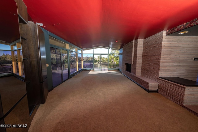 interior space with carpet floors, expansive windows, and vaulted ceiling