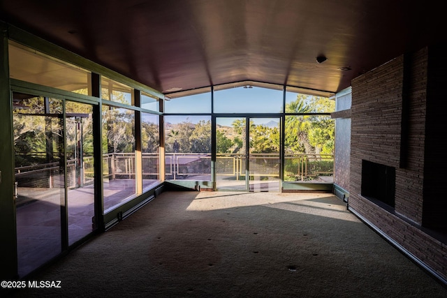 unfurnished sunroom featuring vaulted ceiling and plenty of natural light