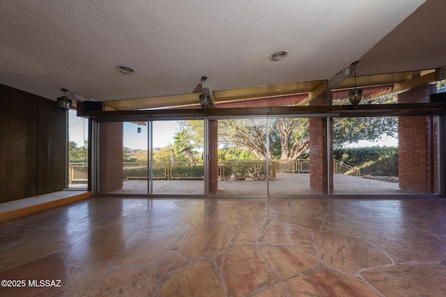 unfurnished room with a textured ceiling and expansive windows