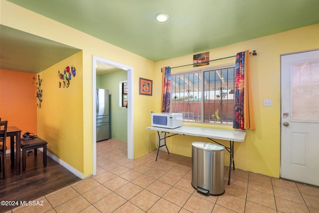 interior space with stainless steel refrigerator and light tile patterned flooring