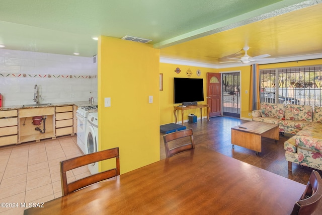 living room with ceiling fan, sink, washer / clothes dryer, light hardwood / wood-style floors, and ornamental molding