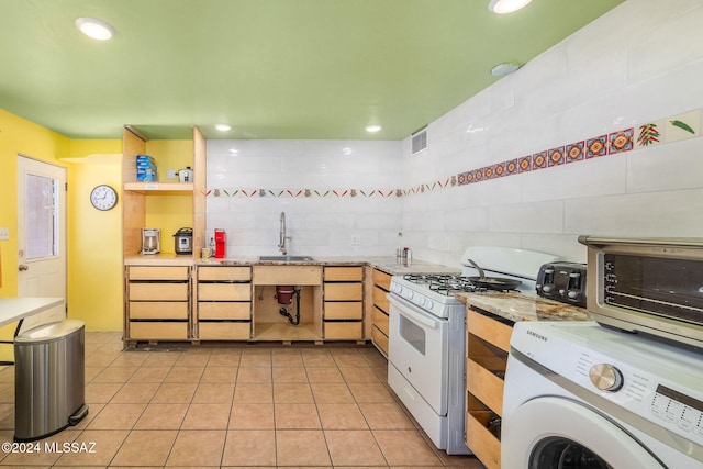 kitchen with white range with gas stovetop, light tile patterned floors, washer / clothes dryer, and sink