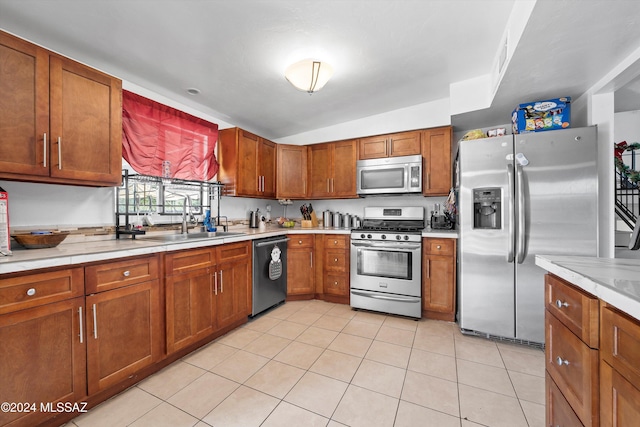 kitchen with sink, light tile patterned floors, stainless steel appliances, and vaulted ceiling