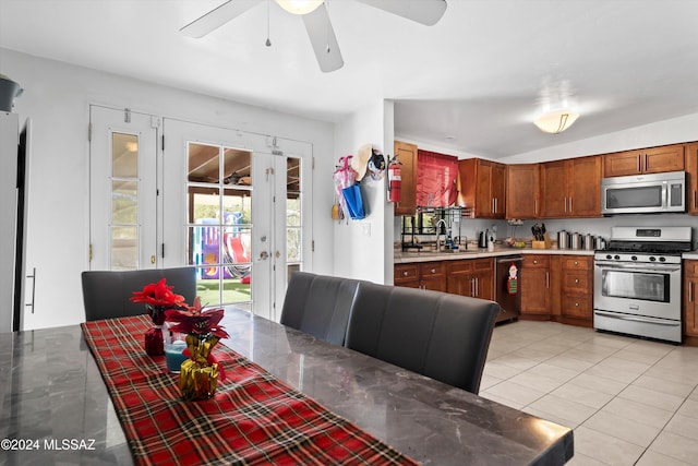 kitchen with appliances with stainless steel finishes, light tile patterned floors, ceiling fan, and sink