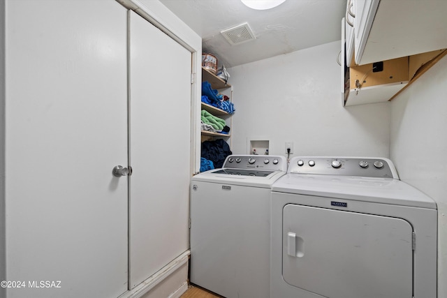 laundry area with light hardwood / wood-style floors and washing machine and clothes dryer