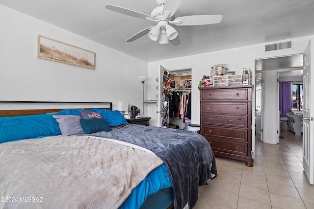 bedroom with a walk in closet, ceiling fan, a closet, and light tile patterned floors