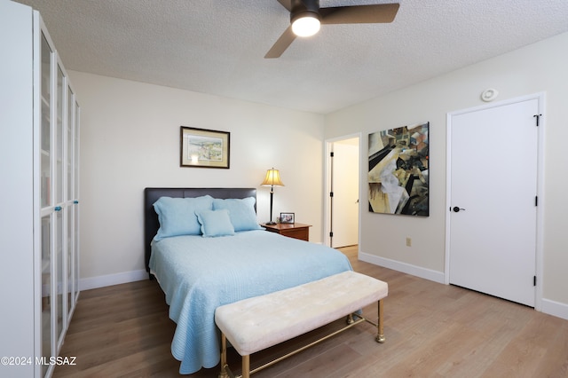 bedroom featuring ceiling fan, wood-type flooring, and a textured ceiling