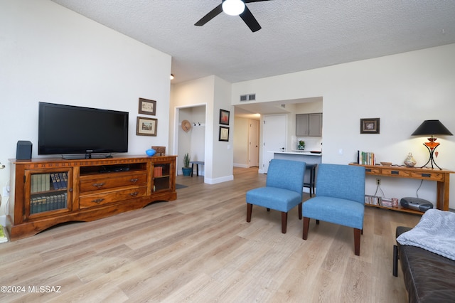 living room with ceiling fan, light hardwood / wood-style floors, and a textured ceiling