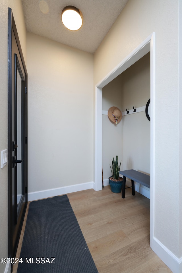 mudroom with a textured ceiling and light hardwood / wood-style floors