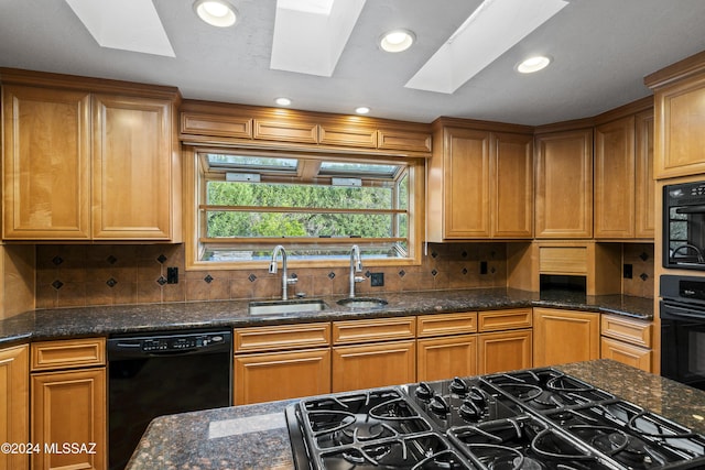 kitchen with black appliances, tasteful backsplash, and a skylight