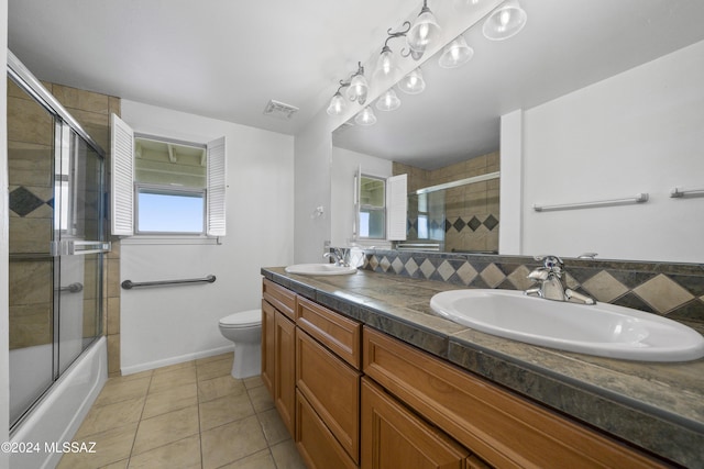 full bathroom with shower / bath combination with glass door, tile patterned floors, vanity, and toilet