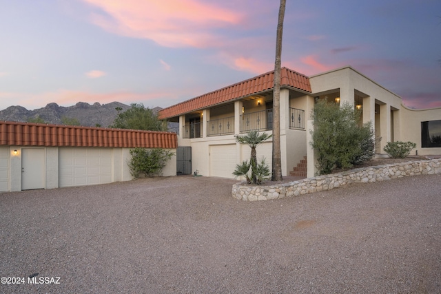 property exterior at dusk featuring a mountain view, a balcony, and a garage