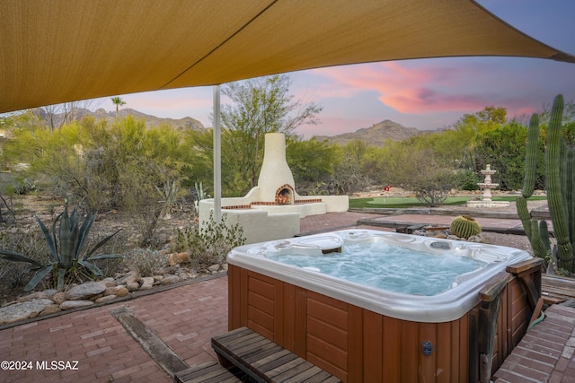 patio terrace at dusk with a mountain view and an outdoor fireplace