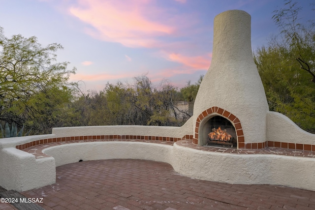 patio terrace at dusk featuring an outdoor fireplace