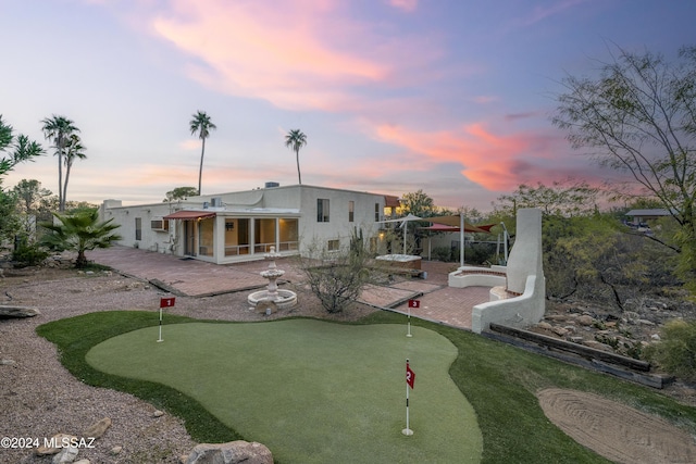 back house at dusk featuring a patio and a sunroom