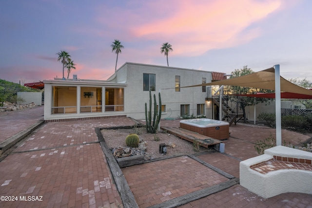 back house at dusk with a patio area and a hot tub