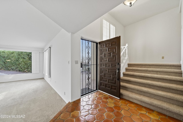 carpeted foyer entrance with vaulted ceiling