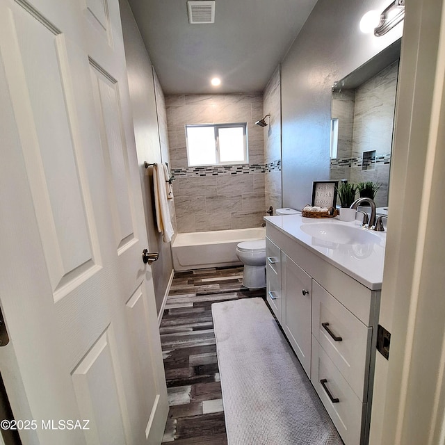 full bathroom featuring toilet, tiled shower / bath, hardwood / wood-style flooring, and vanity