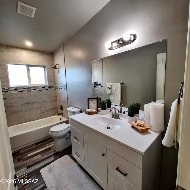 full bathroom featuring wood-type flooring, tiled shower / bath combo, vanity, and toilet