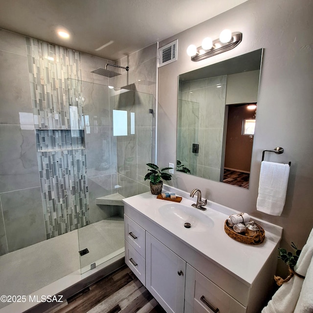 bathroom featuring a tile shower, wood-type flooring, and vanity