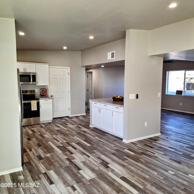 kitchen with dark hardwood / wood-style floors, stainless steel appliances, white cabinetry, and light stone counters