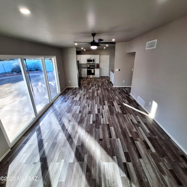 unfurnished living room with ceiling fan, a healthy amount of sunlight, and dark hardwood / wood-style flooring