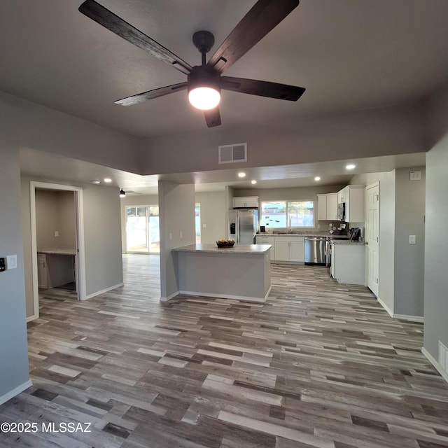 kitchen with white cabinets, stainless steel appliances, sink, light wood-type flooring, and ceiling fan