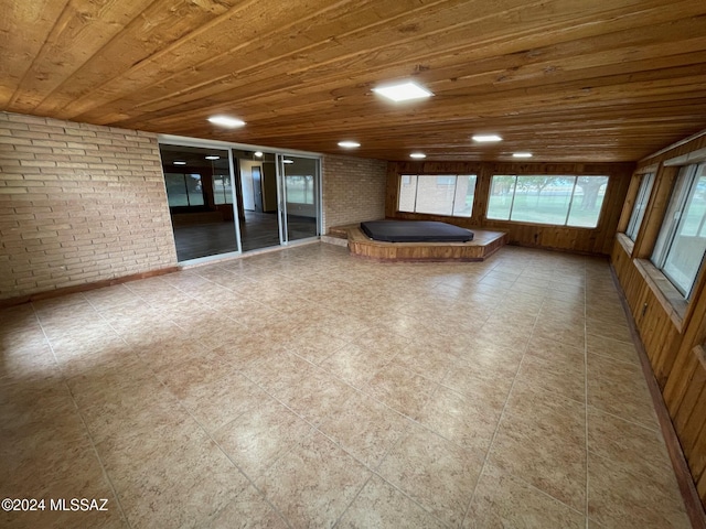 interior space with wooden ceiling and brick wall