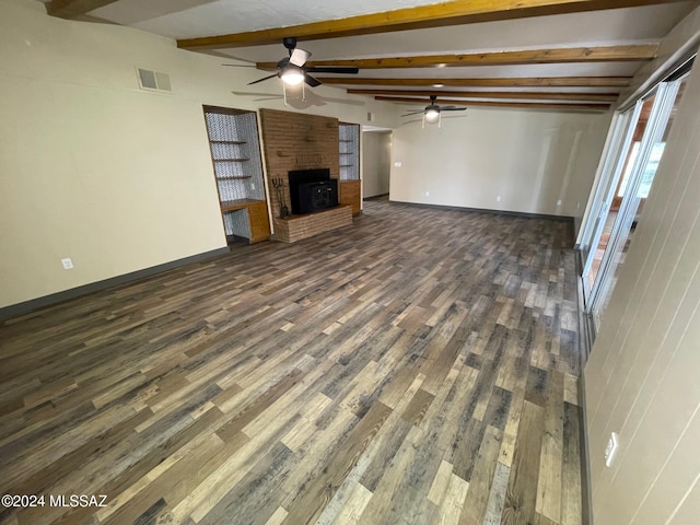 unfurnished living room with dark hardwood / wood-style flooring, lofted ceiling with beams, and a brick fireplace