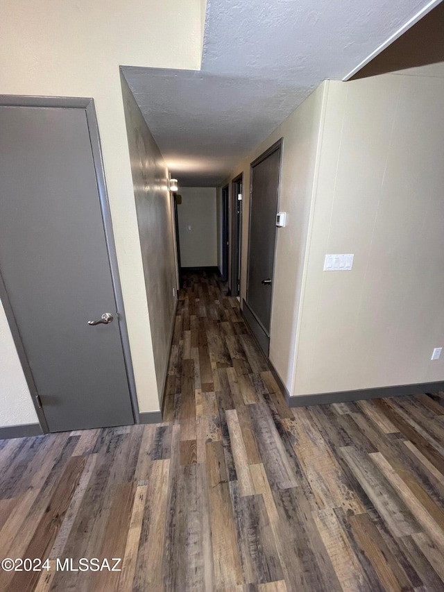 hallway with dark wood-type flooring and a textured ceiling