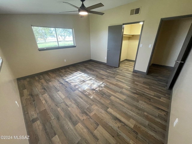 unfurnished bedroom with lofted ceiling, ceiling fan, dark hardwood / wood-style floors, a spacious closet, and a closet