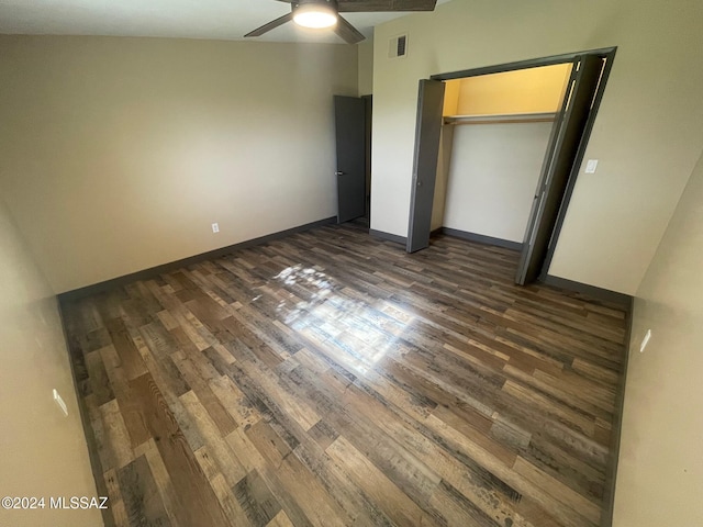 unfurnished bedroom with ceiling fan, a closet, dark wood-type flooring, and lofted ceiling