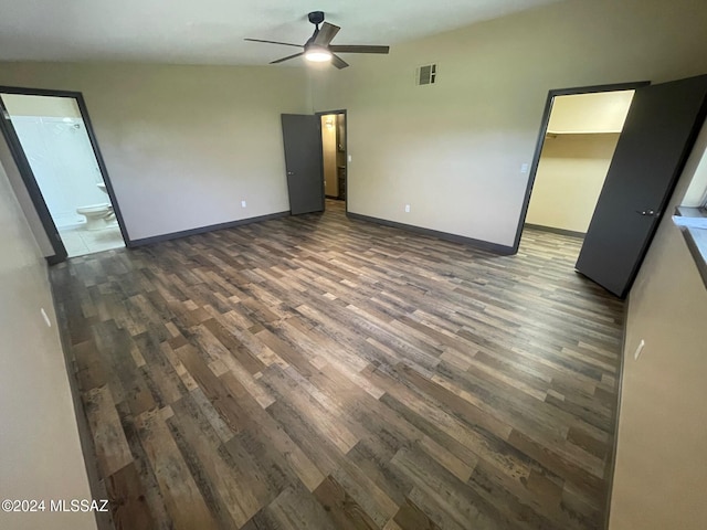 unfurnished bedroom featuring ceiling fan, dark hardwood / wood-style flooring, a walk in closet, and ensuite bath